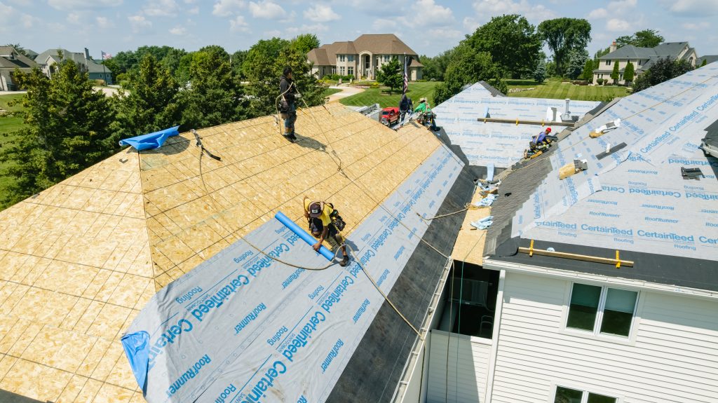 Professional roofers installing new shingles on residential home exterior
